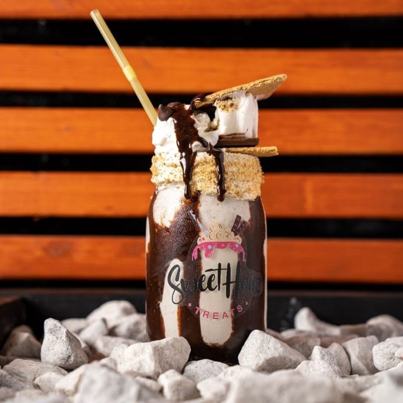 A Sweethaus Treats s'mores milkshake with whipped cream, chocolate drizzle, and graham cracker rim.